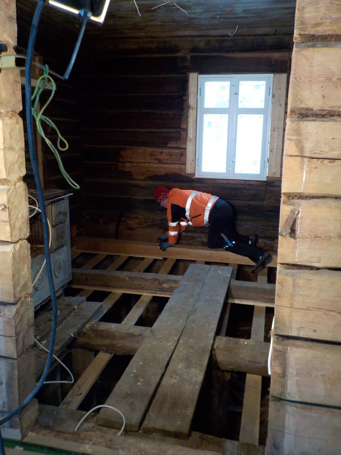 Isäntä konttaa lattiaparrun päällä ja suunnittelee lattian rakennetta.